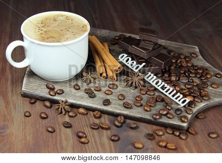 cup of coffee with chocolate, coffee grains, an anisetree, cinnamon and the inscription good morning