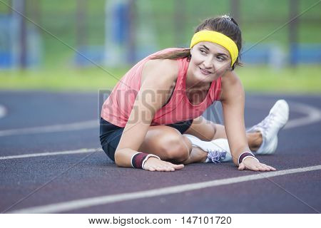 Sport Concepts and Ideas. Caucasian Brunette Female in Athletic Sportgear Having Legs Stretching Excercises Outdoors. Horizontal Shot