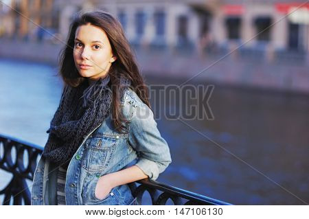 Beautiful Girl In Blue Jeans Jacket And Scarf Straightens Hair Standing Near The Parapet On The Emba