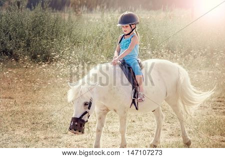 Little girl on the horse. White poni.