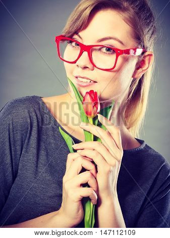 Delicacy and subtlety of women. Young adorable woman with spring flower. Portrait of beauty delicate girl in glasses with red beautiful tulip.