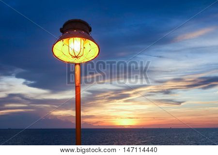 Lighting of warm lamp and lighting of sunset at sea with beautiful sky and clouds in the evening with twilight time on offshore platform.