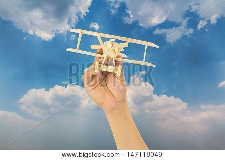 Hand holding wooden airplane model in the sky