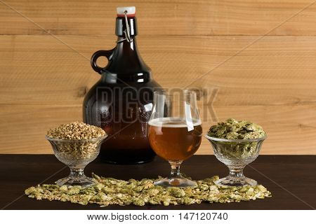 A goblet of beer, with growler, hops and malts