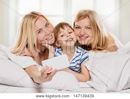 Cheerful relations girlfriends taking picture of themselves on light window background