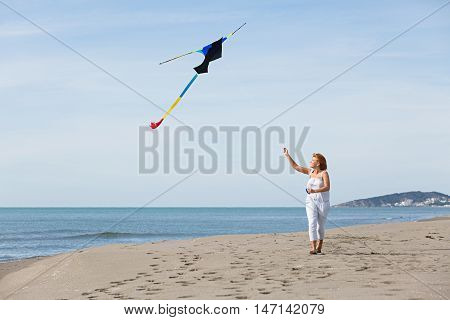 redheaded model holding kite and posing at the seaside