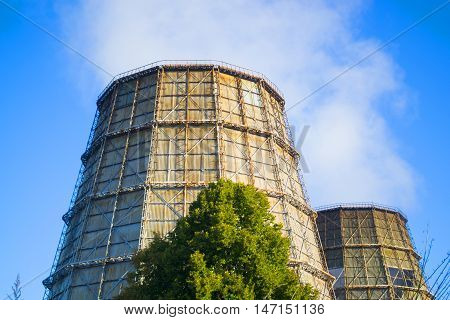 two cooling pipes with a smoke on a sunny day with clear blue sky in summer