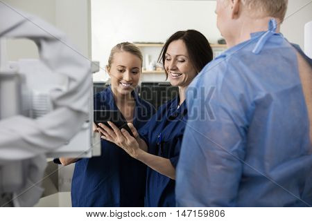 Happy Radiologists Using Tablet Computer While Standing By Patie