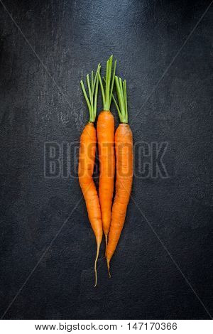 Top view of carrots on black slate background