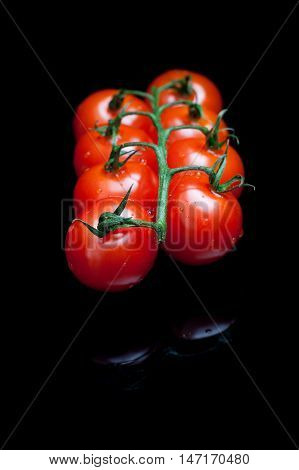 Bunch of red tomatoes on a black reflective background