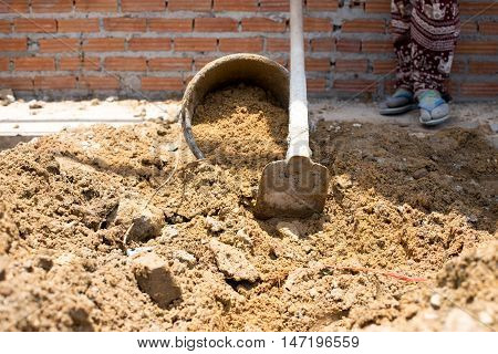 Construction workers are putting sand in the sand bucket in building site