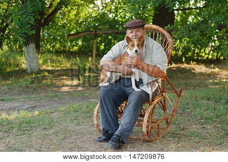 Happy basenji sitting with master on a wicker chair