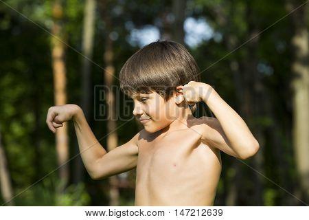 portrait of a boy in nature which shows his muscles