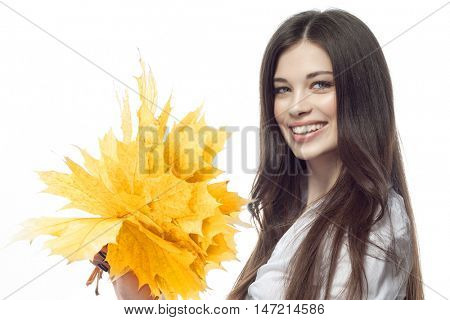 closeup portrait of attractive  caucasian smiling woman brunette isolated on white studio shot lips toothy smile face hairlooking at camera tooth hand holding yellow marple autumn leaves