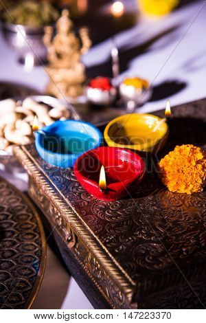 oil lamp or diya with crackers, sweet or mithai, dry fruits, indian currency notes, marigold flower and statue of Goddess Laxmi on diwali night while laxmi pujan or pooja
