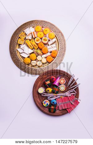 indian sweet food served with assorted fire crackers in separate plate showing diwali concept