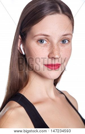 Young beautiful woman with freckles and wireless earphones on her ears. studio shot.