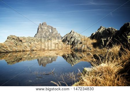 Midi Dossau Peak reflected in a lake. Ossau Valley, Pyrenees National Park, Pyrenees, France.