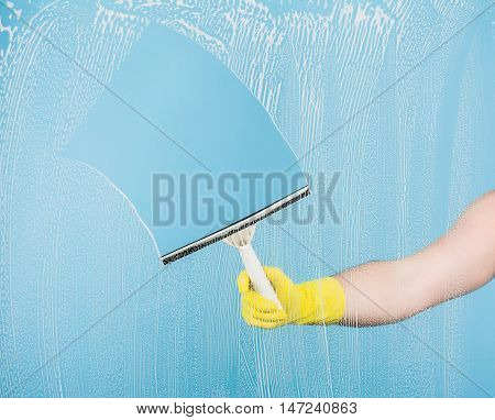 Cleaning conept - hand cleaning glass window pane with detergent and rubber wiper