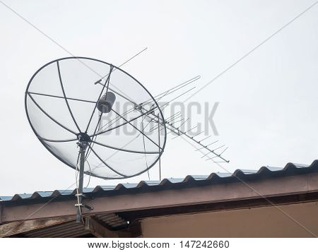 Black satellite dish mounted on a wall outside the house. A drop of