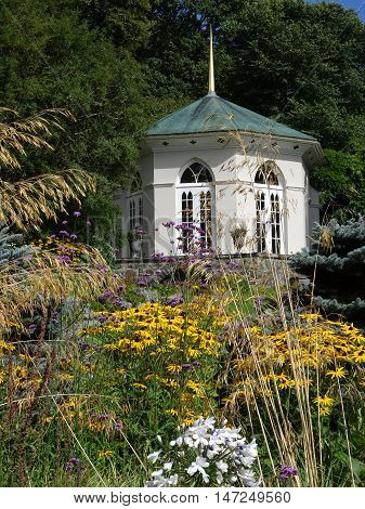 Summerhouse within floral garden and forest backdrop photographed at Colby Woodland Garden near Amroth in Pembrokeshire