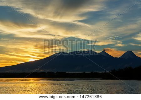 Beautiful sunrise over the volcanoes Kluchevskaya group with reflection in the river Kamchatka.