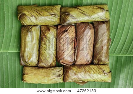 Bananas with Sticky Rice on wooden background. Glutinous rice steamed in banana leaf. Traditional Thai food style Thai name is Khao Tom Mat.