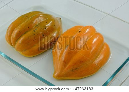 Baked acorn squash halves with oiled skins in glass baking dish