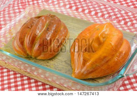 Baked acorn squash halves with oiled skins in glass baking dish