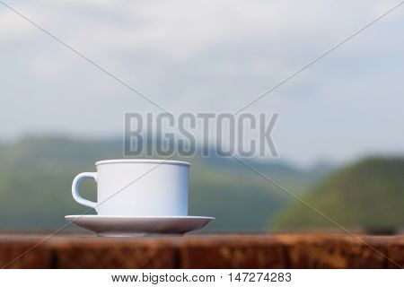 Coffee cup on wooden table and mountain (vintage background)