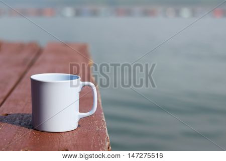 Coffee cup on wooden floor and river (vintage background)