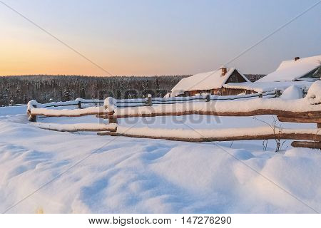 A small house behind a fence in the snow