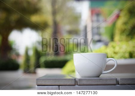 Coffee cup on table in garden (vintage background)