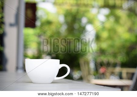 Coffee cup on table in garden (vintage background)