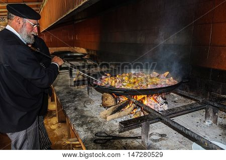 VALENCIA, SPAIN - MARCH 21, 2015: Local chef preparing a traditional Valencian paella with meat and chicken in Valencia Spain