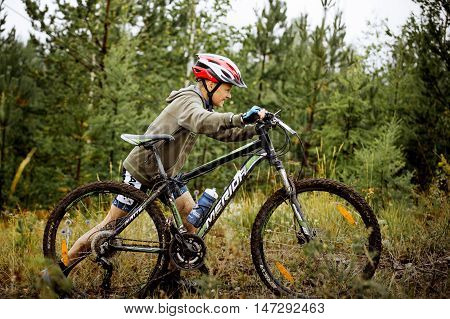 Revda Russia - July 31 2016: teen boy athlete uphill on foot with his bicycle during Regional competitions on cross-country bike