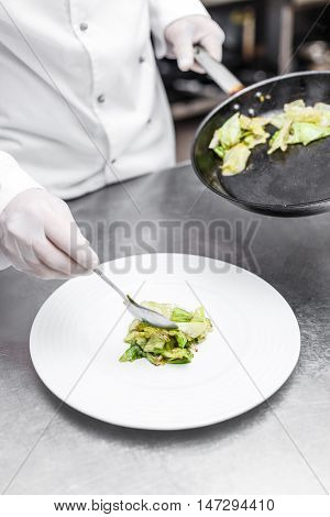 Chef add iceberg lettuce on white plate