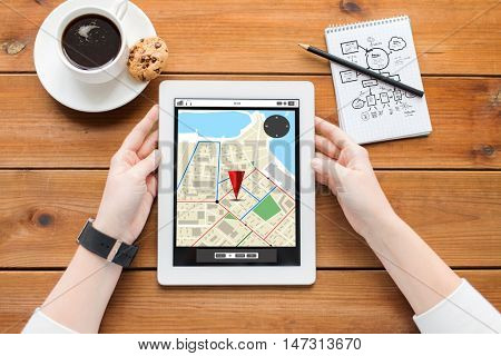 business, location, education, technology and people concept - close up of woman with gps navigator map on tablet pc computer screen and coffee on wooden table with gps navigator map on screen