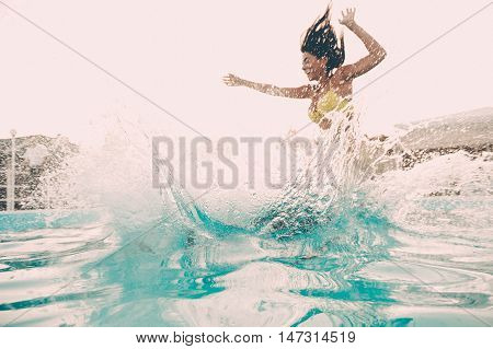 Pool fun. Beautiful young woman jumping into the outdoor swimming pool