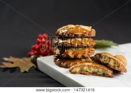 Typical Dutch filled spicy cookies with almonds on autumn colored and dark background