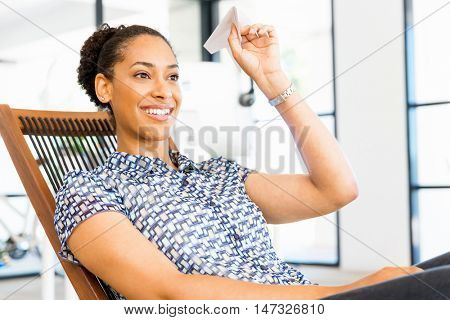 Young woman in office holding paper plane