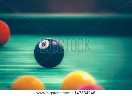 Black billard ball number eight on green billard table