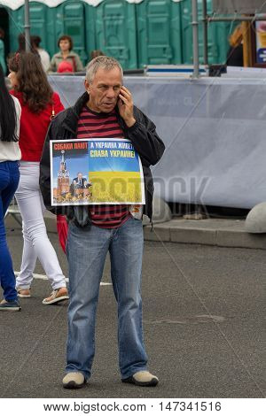 Kiev Ukraine - Auguct 24 2016: Man on Independence Square during the celebration of Independence Day holding a poster with an inscription Dogs bark and Ukraine is living! Glory to Ukraine "in Russian