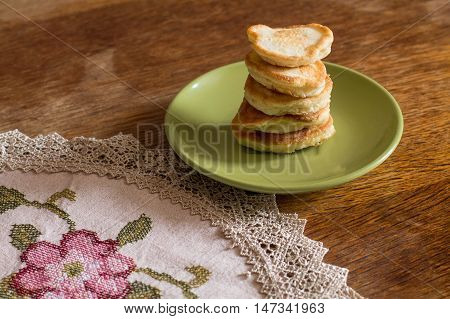 Stack of olady (traditional ukrainian pancakes) in green plate on wood table.