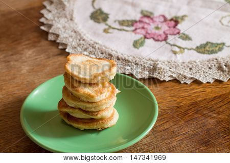 Stack of olady (traditional ukrainian pancakes) in green plate on wood table.