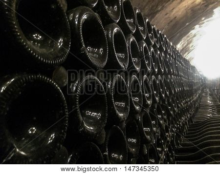 Wide angle image of a stack of wine bottles in an old dark wine cellar. Natural available light only.
