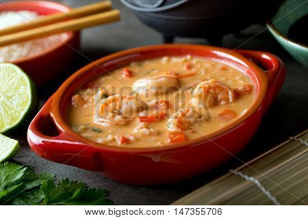 A bowl of delicious Thai red curry coconut shrimp soup with rice.