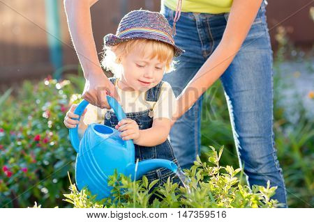 Kid boy toddler helping mother in the garden sunny summertime