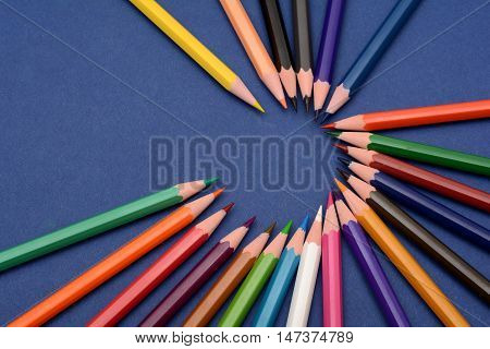 Set of Colorful pencils making a circle on blue background.