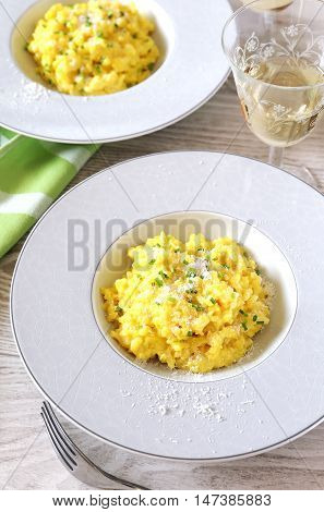 Yellow risotto with saffron cheese and onion shallot plant and wineglass